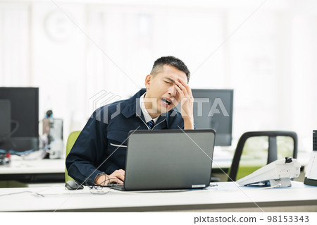 A man in work clothes who is worried in the office 98153343