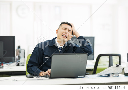 A man in work clothes who is worried in the office 98153344