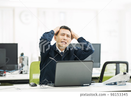 A man in work clothes who is worried in the office 98153345