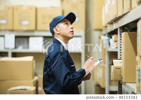 A man in work clothes inspecting at a distribution warehouse 98153381
