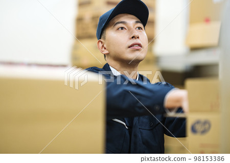A man in work clothes working in a distribution warehouse 98153386