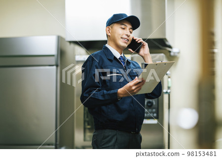 Equipment maintenance worker talking on smartphone 98153481