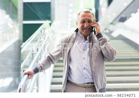Middle aged man with phone going down stairs in mall 98154071
