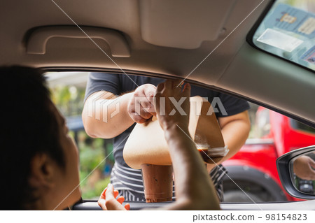 Waiter delivery iced coffee drink to customer in the car. Waiter delivery iced coffee drink to customer in the car. 98154823