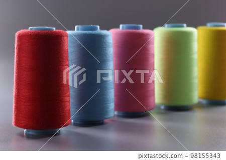 Multicolored thread spools on gray background. Set of colored threads 98155343