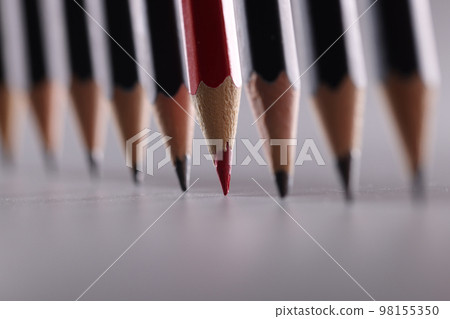 Red pencil stands out from many identical black ones 98155350
