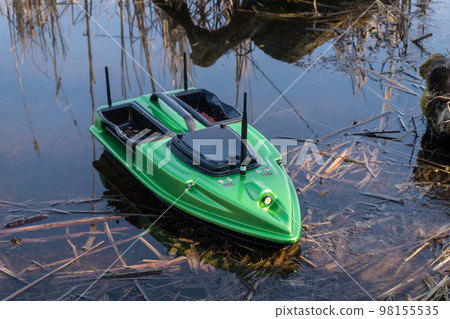 Bait Boat on water. Wireless remote control green fishing feeder, fish finder boat. Bait Boat on water. Wireless remote control green fishing feeder, fish finder boat. 98155535