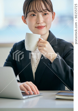 Young woman taking a break with coffee at her desk Young woman taking a break with coffee at her desk 98155725