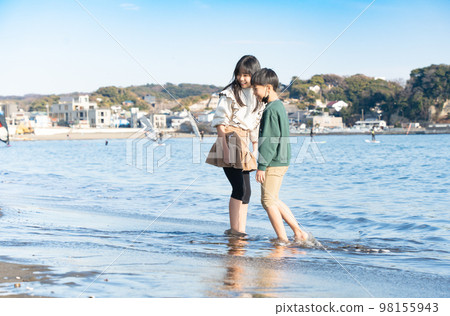 冬天在沙灘上玩耍的男孩和女孩 98155943