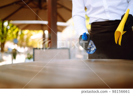 Disinfecting to prevent COVID-19. Waiter cleaning the table with Disinfectant Spray in a restaurant. 98156661