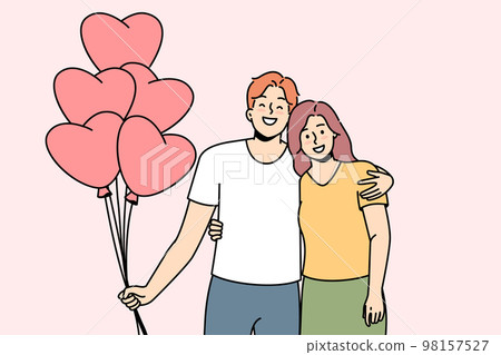 Smiling couple hug holding heart shaped balloons Smiling couple hug holding heart shaped balloons 98157527