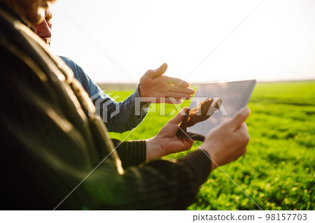 Two Farmers uses specialized app on digital tablet for checking wheat. Agriculture, ecology concept. Two Farmers uses specialized app on digital tablet for checking wheat. Agriculture, ecology concept. 98157703
