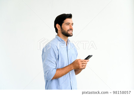 Portrait of smiling macho bearded guy in blue t-shirt using smartphone standing over white background. Portrait of smiling macho bearded guy in blue t-shirt using smartphone standing over white background. 98158057