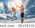 Sport man and woman exercise on beach at sunset 98158216