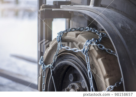 Cargo loader in winter on snow. The loader ride on snow with chains on the wheels to reduce slippage and spin. Driving safety in winter conditions Cargo loader in winter on snow. The loader ride on snow with chains on the wheels to reduce slippage and spin. Driving safety in winter conditions 98158657