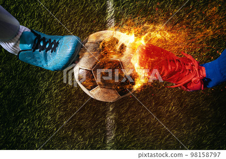 Two soccer players challenge each other at the stadium ready to kick a fiery ball Two soccer players challenge each other at the stadium ready to kick a fiery ball 98158797