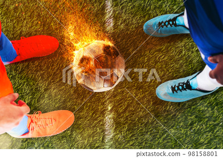 Two soccer players challenge each other at the stadium ready to kick a fiery ball Two soccer players challenge each other at the stadium ready to kick a fiery ball 98158801