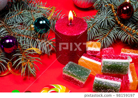 Marmalade on a red background with a burning candle. Banner for confectionery with Christmas decorations. Gifts for New Year 2021. 98159197