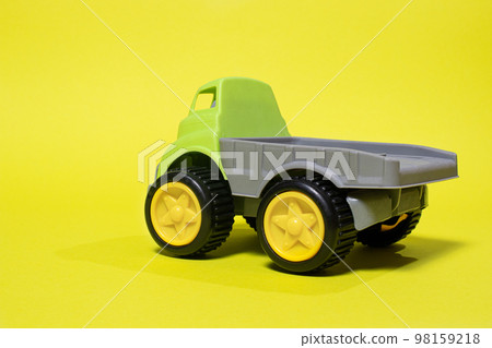 Toy truck car on a yellow background - construction equipment for children. Bright children's plastic toys, dump truck childhood. 98159218