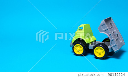 Toy truck car on a blue background - construction equipment for children. Bright children's plastic toys, dump truck childhood. Copyspace banner place for text. Toy truck car on a blue background - construction equipment for children. Bright children's plastic toys, dump truck childhood. Copyspace banner place for text. 98159224