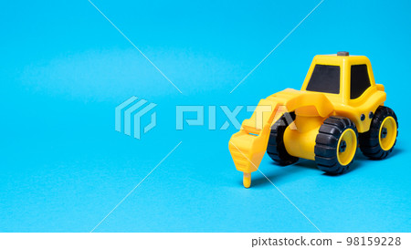 Toy tractor drill on a blue background with a place for text, a banner for a children's toy store Toy tractor drill on a blue background with a place for text, a banner for a children's toy store 98159228