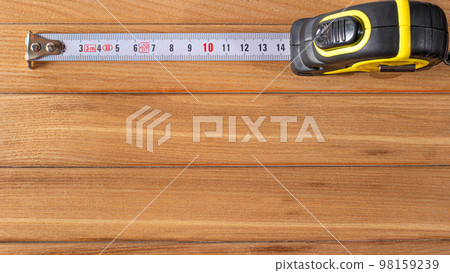 Measuring tape with numbers centimeters on a wood brown background. Construction tools. Banner with place for text 98159239