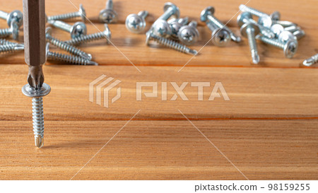 The screwdriver twists the self-cut into wooden boards. Construction tools, home repairs. The screwdriver twists the self-cut into wooden boards. Construction tools, home repairs. 98159255
