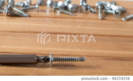 A screwdriver and self-cutters on a brown wooden background. Building tools to repair the house. A screwdriver and self-cutters on a brown wooden background. Building tools to repair the house. 98159256