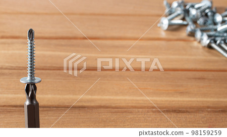 A screwdriver and self-cutters on a brown wooden background. Building tools to repair the house. 98159259