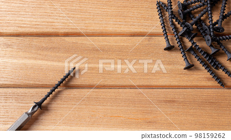 A screwdriver and self-cutters on a brown wooden background. Building tools to repair the house. 98159262