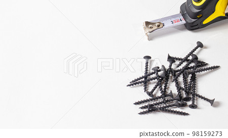 Nails and measuring tape roulette on a white background. A banner with a place for text with a white background. Construction tools. 98159273