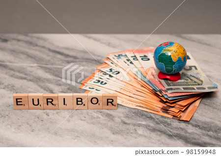 Word EURIBOR Is Written In Wooden Letters, Near Stack of Money Of 5, 10, 20 and 50 Euro Banknotes and Globe. Word EURIBOR Is Written In Wooden Letters, Near Stack of Money Of 5, 10, 20 and 50 Euro Banknotes and Globe. 98159948