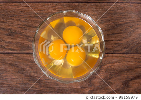 Three raw eggs in a glass bowl. The contents of chicken eggs for cooking eggs and other dishes. Three raw eggs in a glass bowl. The contents of chicken eggs for cooking eggs and other dishes. 98159979