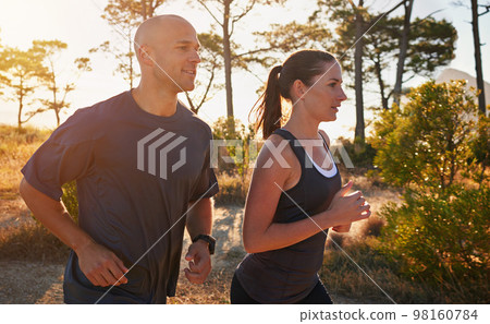 Running off the beaten path. a young couple doing a trail run together. 98160784