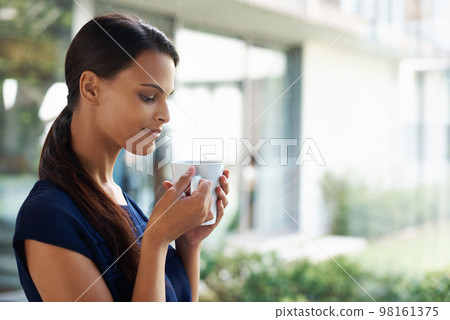 Enjoy a cup of inspiration. an attractive young woman enjoying a freshly brewed cup of coffee. 98161375