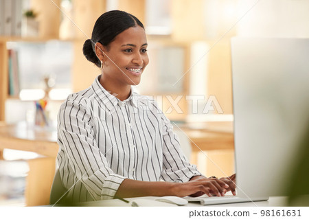 Happy business woman worker on computer working in the office at a corporate company. Smile, planning and market online research female entrepreneur working on a desktop in her workplace while typing 98161631
