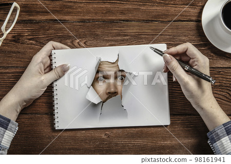 Male face through the hole in paper Male face through the hole in paper 98161941