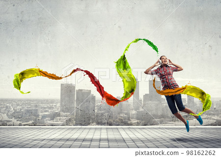 Woman wearing headphones jumping . Mixed media Woman wearing headphones jumping . Mixed media 98162262