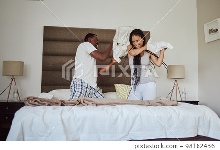 Love, pillow fight and playful with a black couple having fun in the bedroom of their home tofether in the morning. Dating, funny and joking with a man and woman playing or bonding on the bed 98162436
