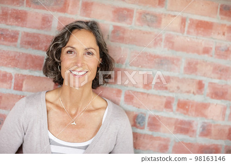 Geting some fresh air. A mature woman leaning against a facebrick wall. Geting some fresh air. A mature woman leaning against a facebrick wall. 98163146