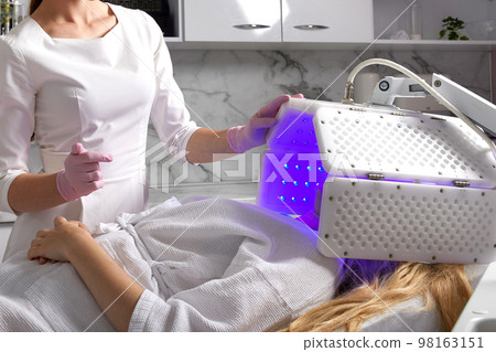 Young woman having photodynamic therapy in beauty salon 98163151