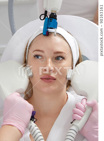 Cosmetology image of hands of several doctors holding laser equipment over female face. Beauty and Cosmetology concept 98163161