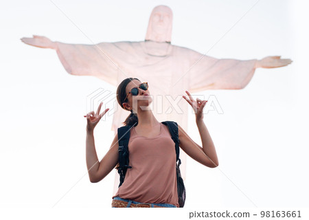 Feeling the Rio vibe. a woman posing for a picture in front of a statue of Christ in Brazil. Feeling the Rio vibe. a woman posing for a picture in front of a statue of Christ in Brazil. 98163661