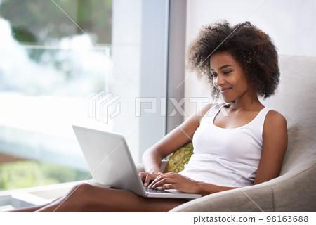 Some early morning catching up with a friend. Shot of a beautiful young woman in pajamas using a laptop. Some early morning catching up with a friend. Shot of a beautiful young woman in pajamas using a laptop. 98163688