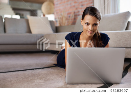 Relaxing with my tech. an attractive young woman using her laptop while relaxing on the floor at home. Relaxing with my tech. an attractive young woman using her laptop while relaxing on the floor at home. 98163697