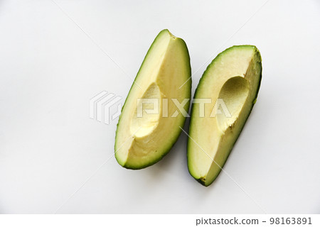 Green avocado fruit cut into slices on a white background. Avocado on a white plate. Avocado slices and halves 98163891