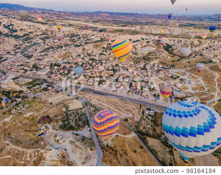 Colorful hot air balloons flying over at fairy chimneys valley in Nevsehir, Goreme, Cappadocia Turkey. Spectacular panoramic drone view of the underground city and ballooning tourism. High quality Colorful hot air balloons flying over at fairy chimneys valley in Nevsehir, Goreme, Cappadocia Turkey. Spectacular panoramic drone view of the underground city and ballooning tourism. High quality 98164184