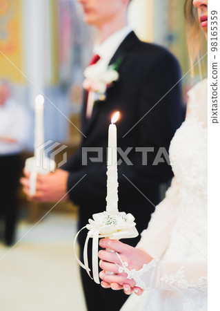 Bride and groom holding candles in church Bride and groom holding candles in church 98165359