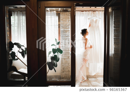 Beautiful bride wearing fashion wedding dress with feathers with luxury delight make-up and hairstyle, studio indoor photo shoot 98165367