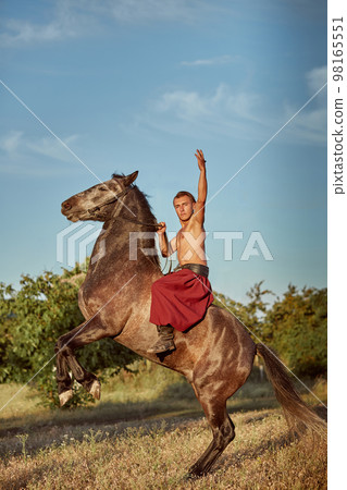 Handsome man cowboy riding on a horse - background of sky and trees Handsome man cowboy riding on a horse - background of sky and trees 98165551